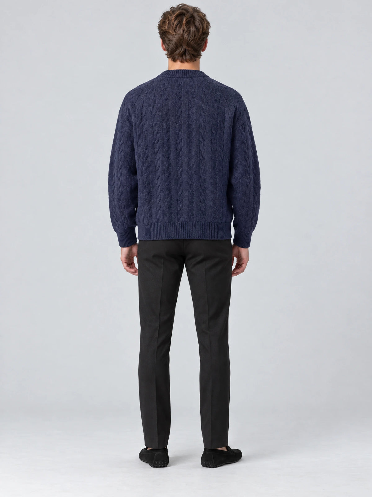Rear studio view of a model wearing a Navy crewneck cardigan with cable-knit texture and ribbed cuffs and hem.