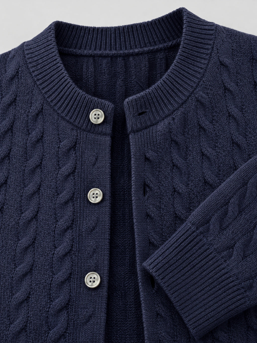 Close-up of a Navy men's crewneck cardigan with cable-knit texture, ribbed collar and cuffs, and button-front closure.