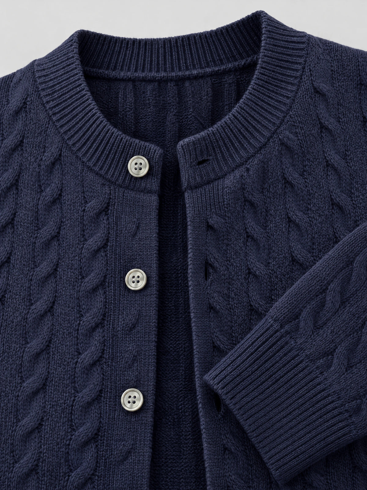Close-up of a Navy men's crewneck cardigan with cable-knit texture, ribbed collar and cuffs, and button-front closure.