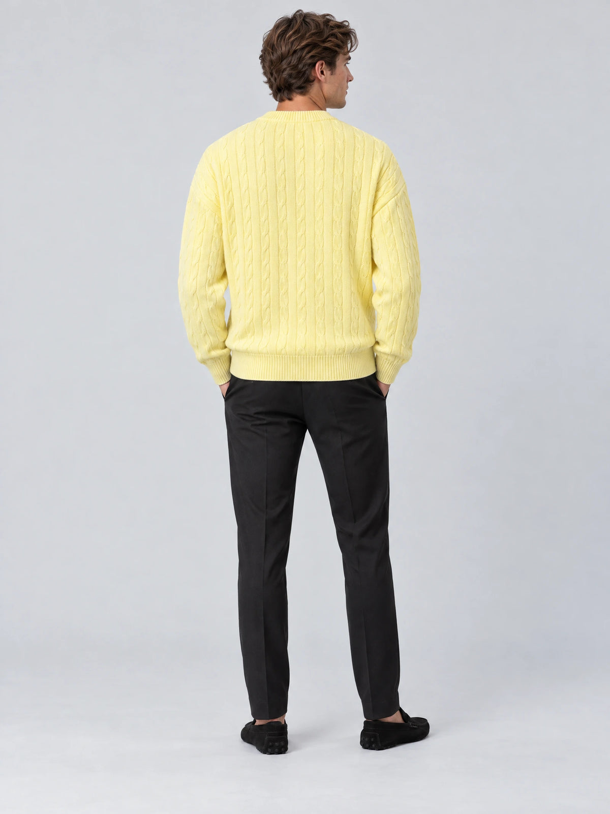 Rear studio view of a model wearing a Yellow crewneck cardigan with a cable-knit texture and ribbed hem.