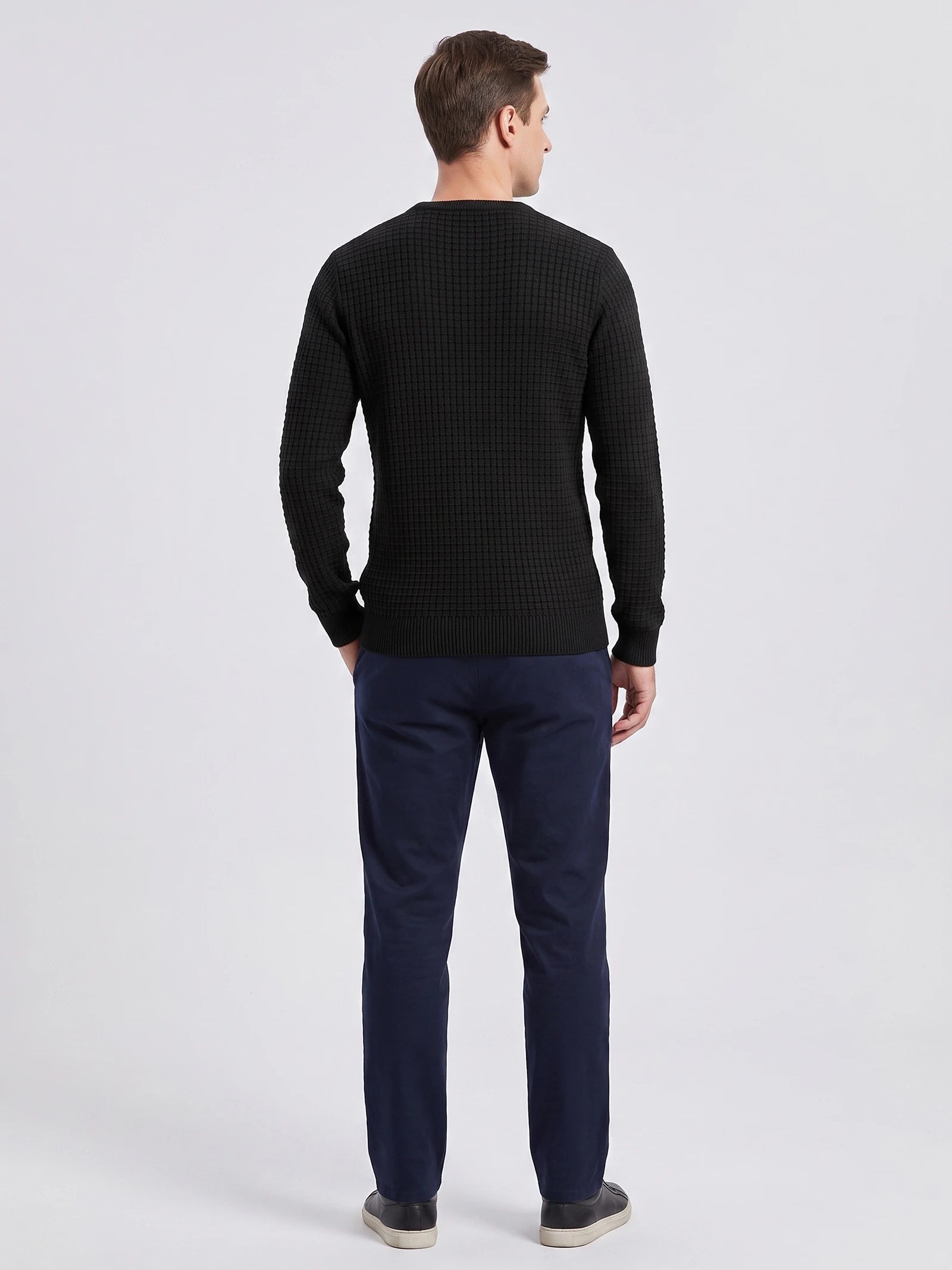 Rear studio view of a model wearing a Black men's crewneck sweater with textured knit and ribbed cuffs and hem.