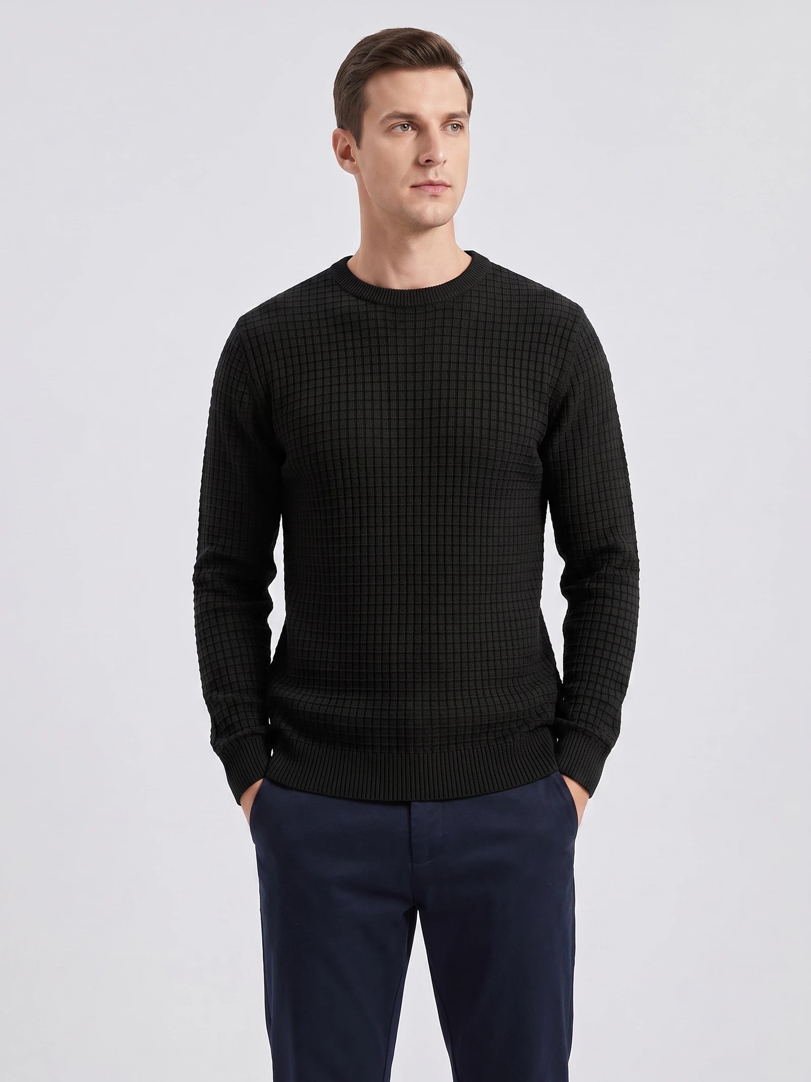 Front studio view of a model wearing a Black men's crewneck sweater with textured grid knit and ribbed trim.