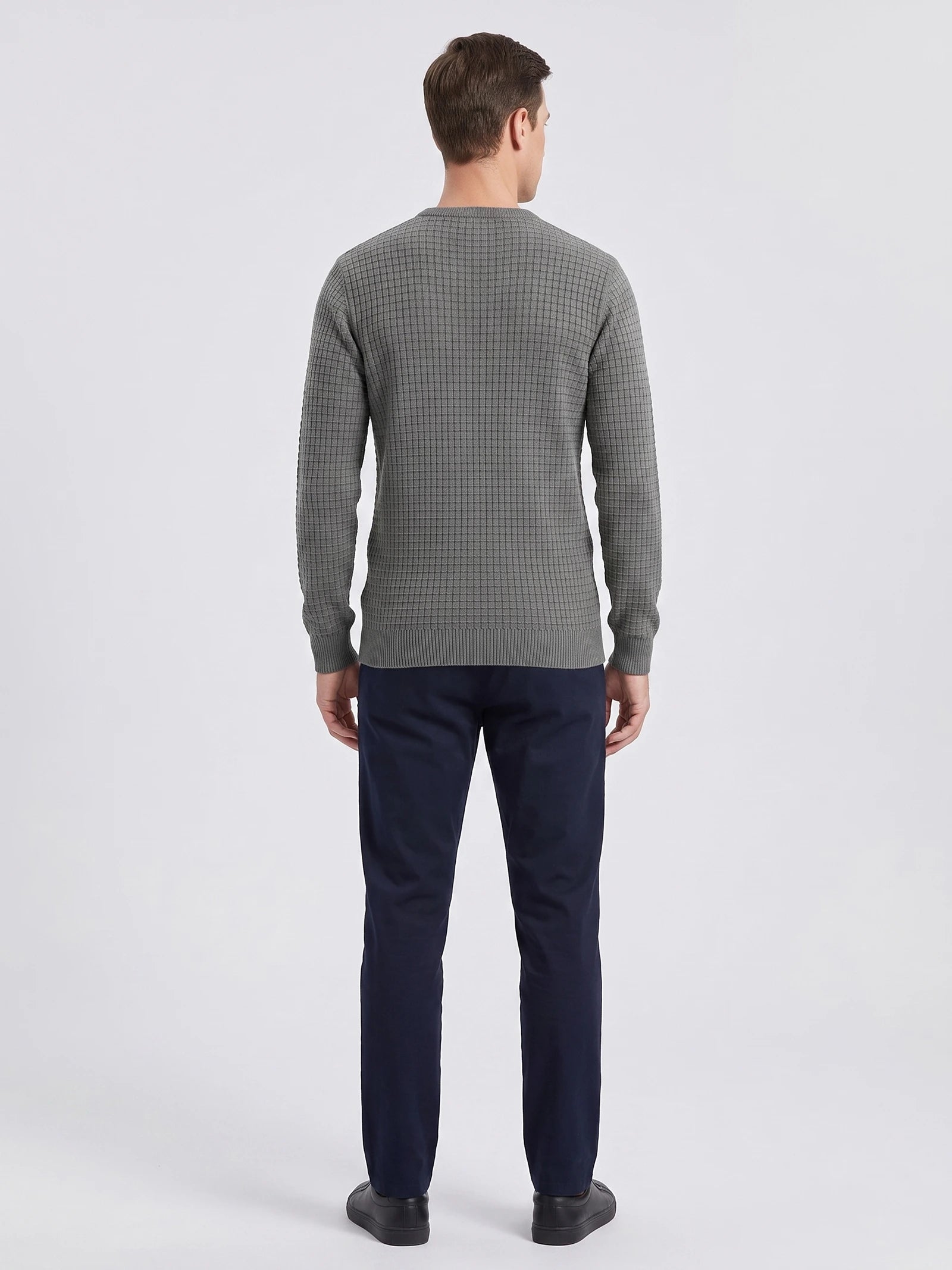 Rear studio view of a model wearing a Gray men's crewneck sweater with a textured grid-knit pattern and ribbed hem and cuffs.