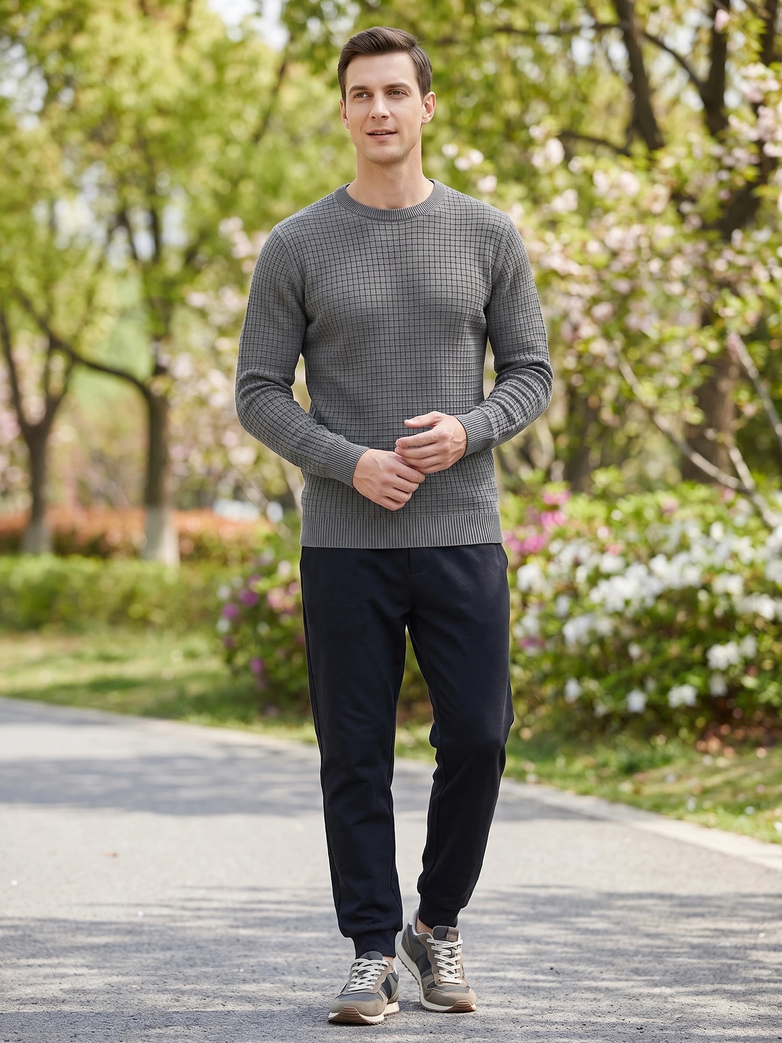 Model wearing a Gray men's crewneck sweater with a textured knit pattern while walking along a garden path.