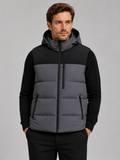 Front view of a man wearing a dark gray hooded puffer vest with a windproof shell, thick insulation, sleeveless design, and full zip front
