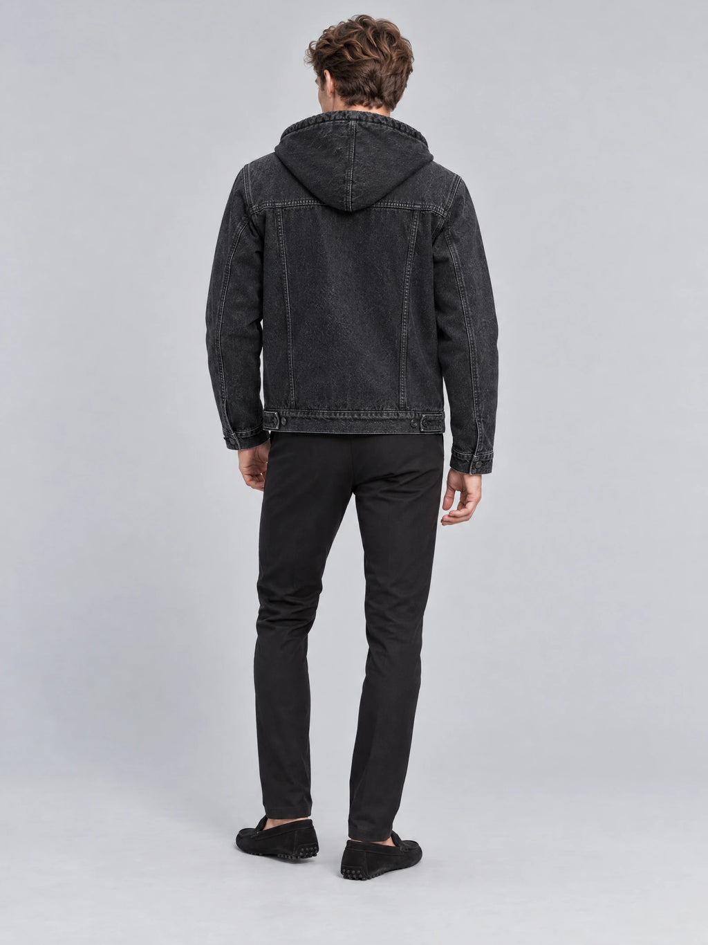 Rear studio view of a model wearing a Black mens denim hoodie jacket with a hood, back yoke stitching, and adjustable hem tabs.