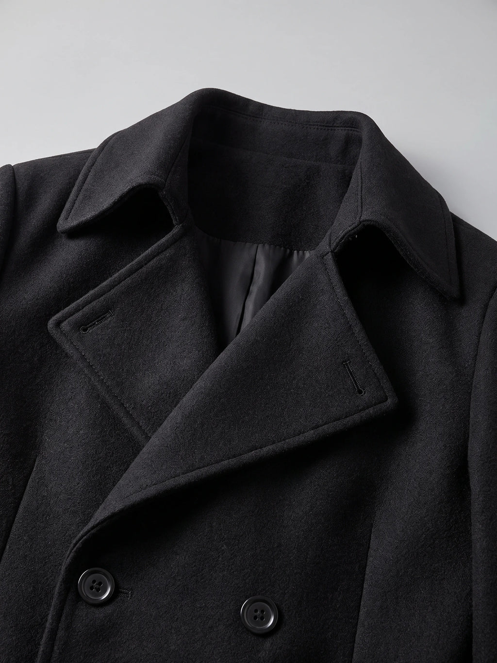 Close-up of the Black men's trench coat showcasing the turn-down collar, lapels, lining, and double-breasted buttons.