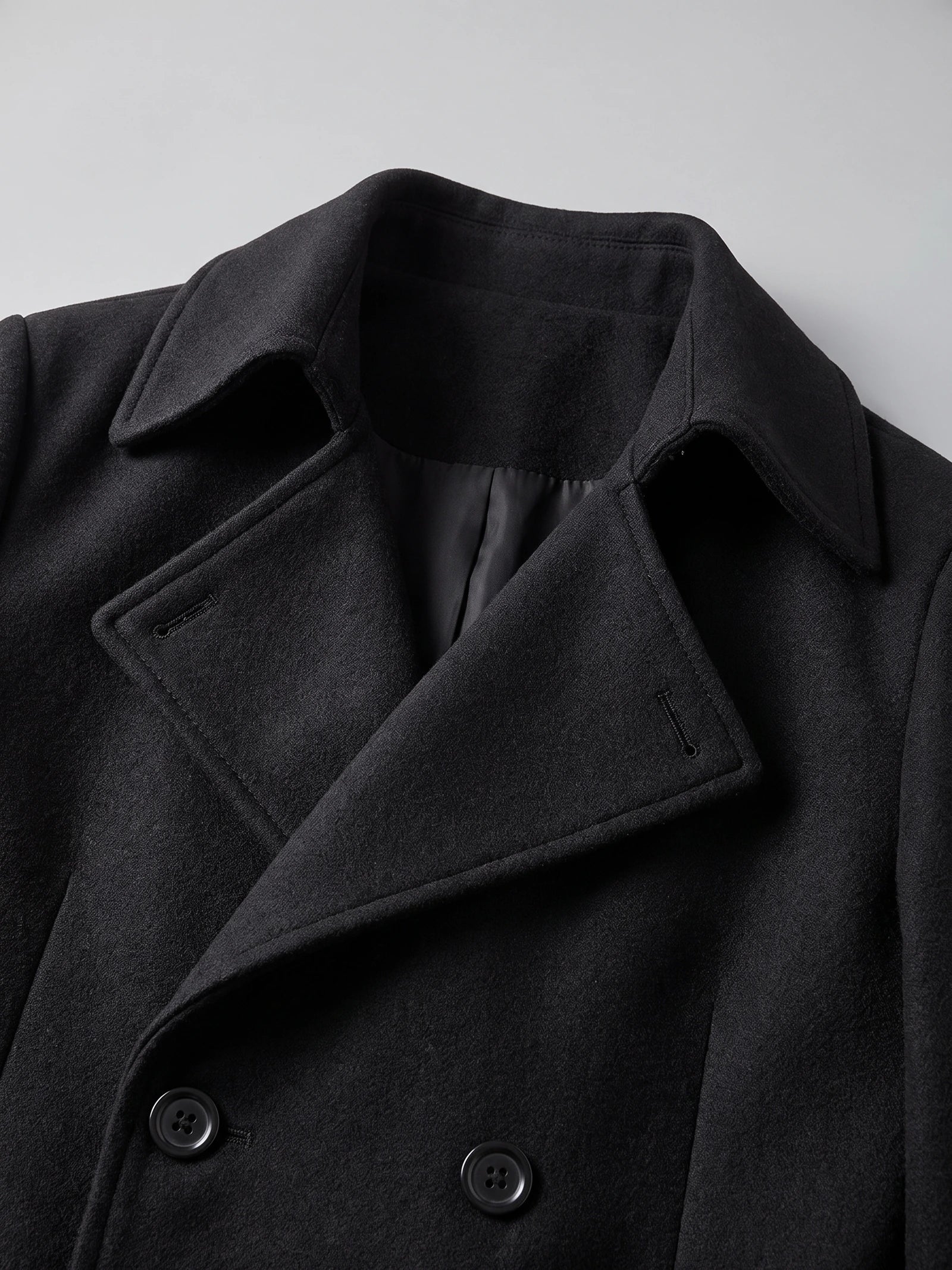 Close-up of the Black men's trench coat showcasing the turn-down collar, lapels, lining, and double-breasted buttons.