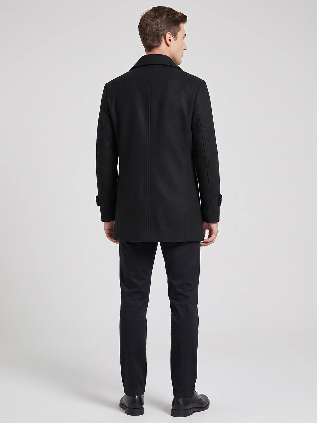 Rear studio view of a model wearing a Black wool Peacoat with a structured collar and center back seam.