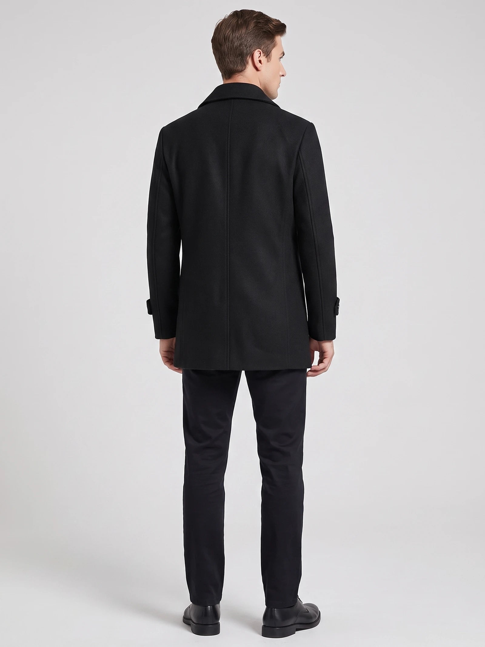 Rear studio view of a model wearing a Black wool Peacoat with a structured collar and center back seam.