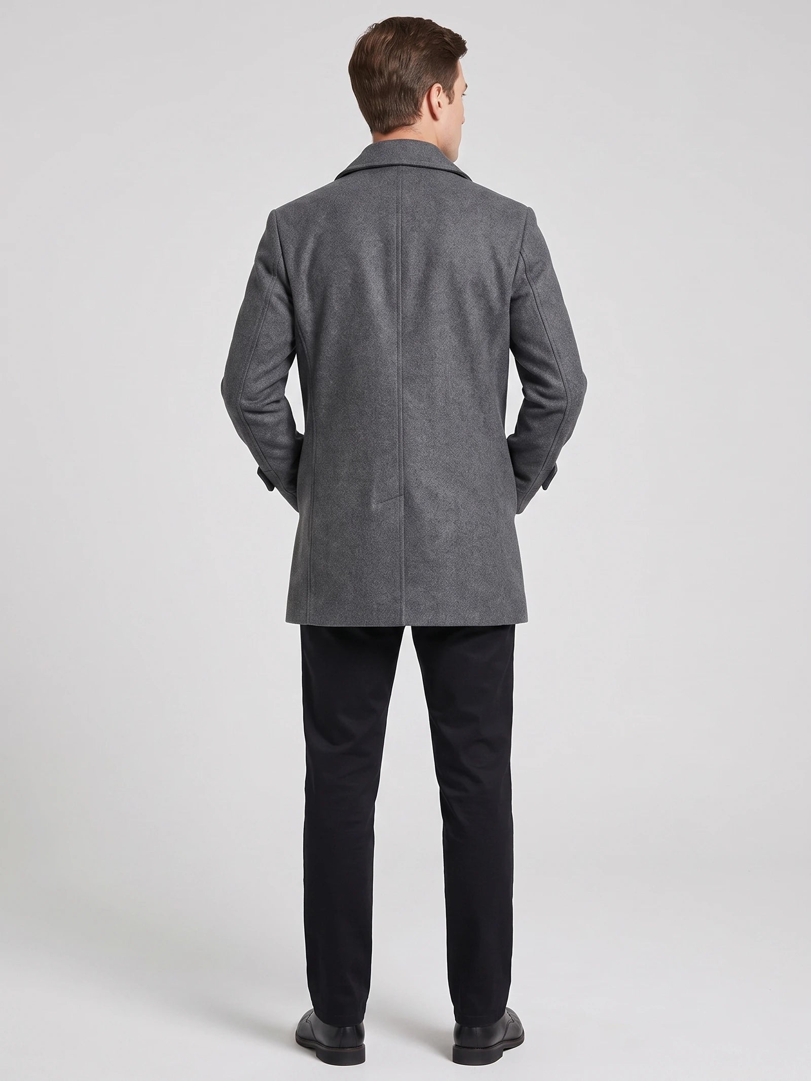 Rear view of a model wearing a Gray wool Peacoat with a back vent and structured collar.
