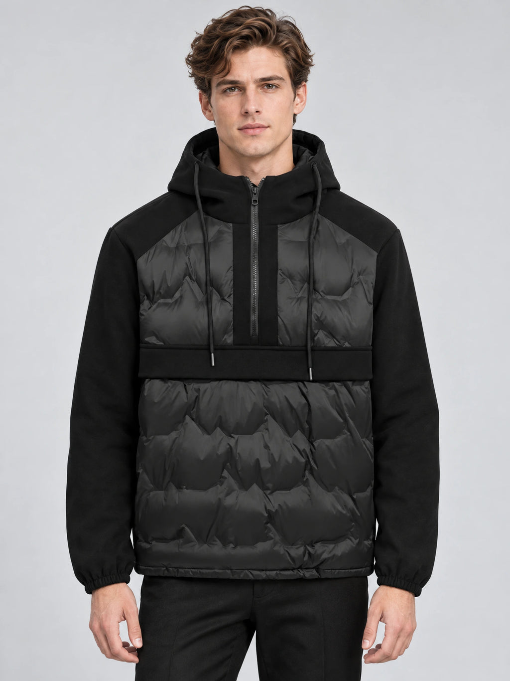 Front studio view of a model wearing a Black hooded down jacket with a half-zip placket and quilted panels.