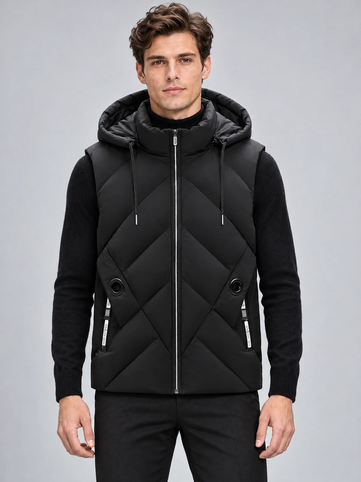Front studio view of a model wearing a Black Down Vest with a zip-front closure, padded hood, and diagonal quilted panels.