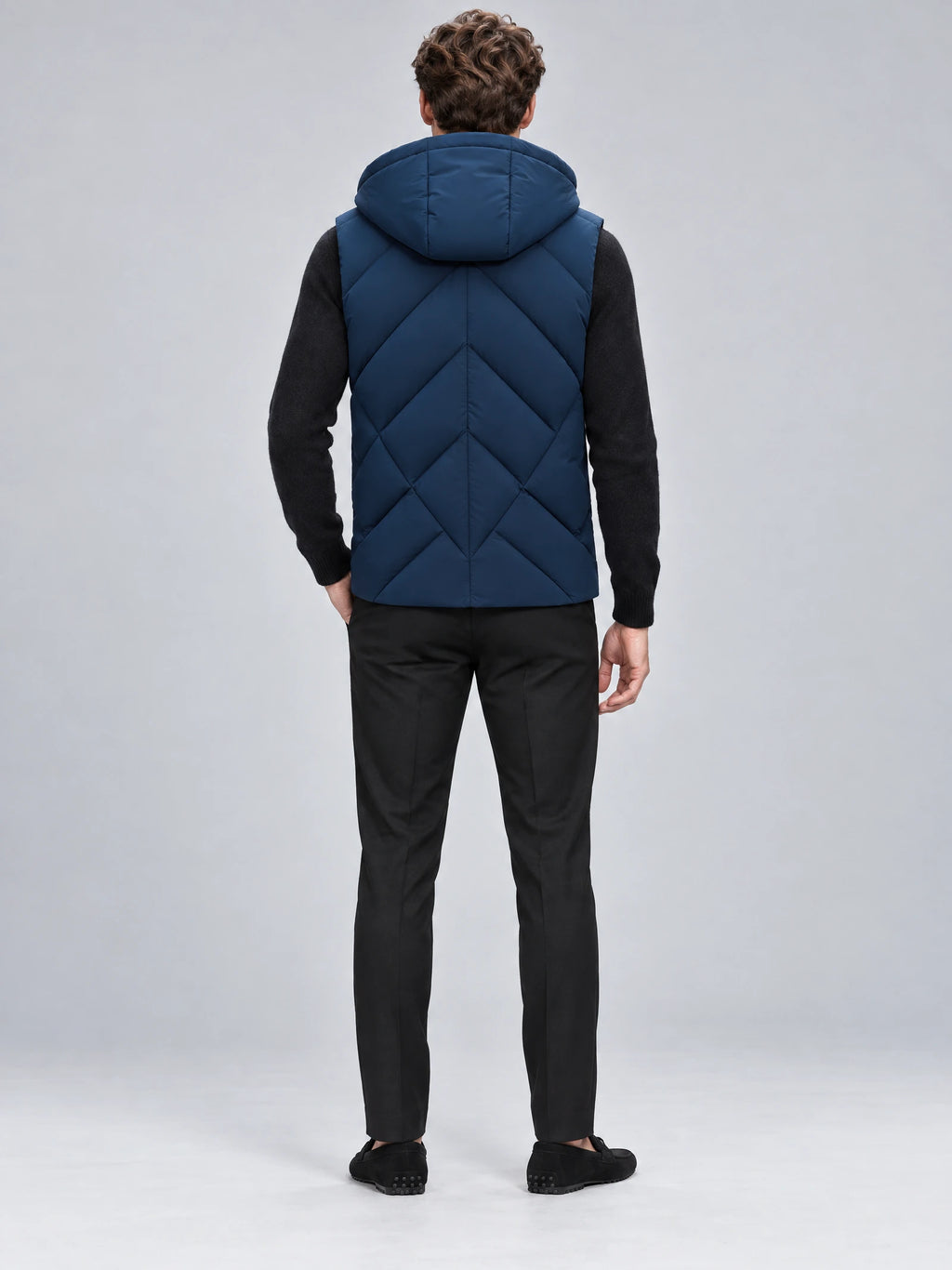 Rear studio view of a model wearing a Navy Down Vest with a hood and chevron quilted back.