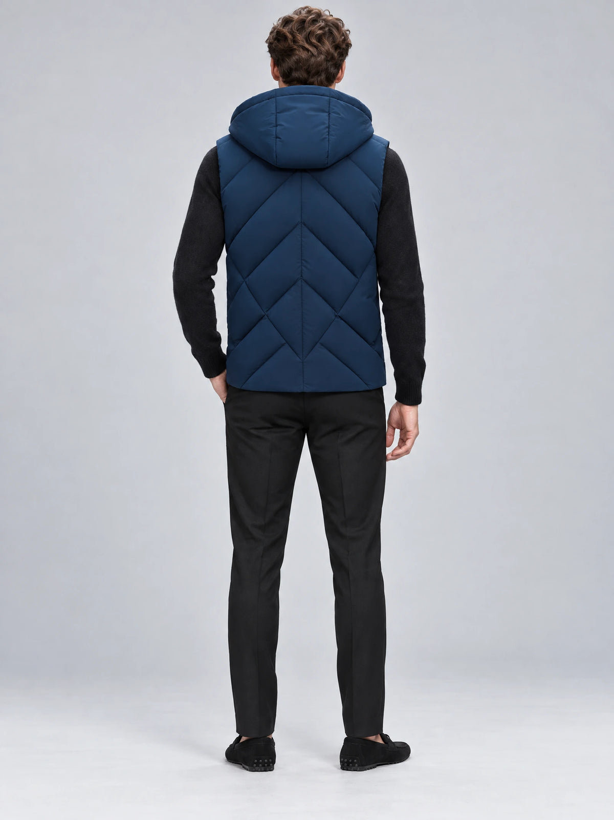 Rear studio view of a model wearing a Navy Down Vest with a hood and chevron quilted back.