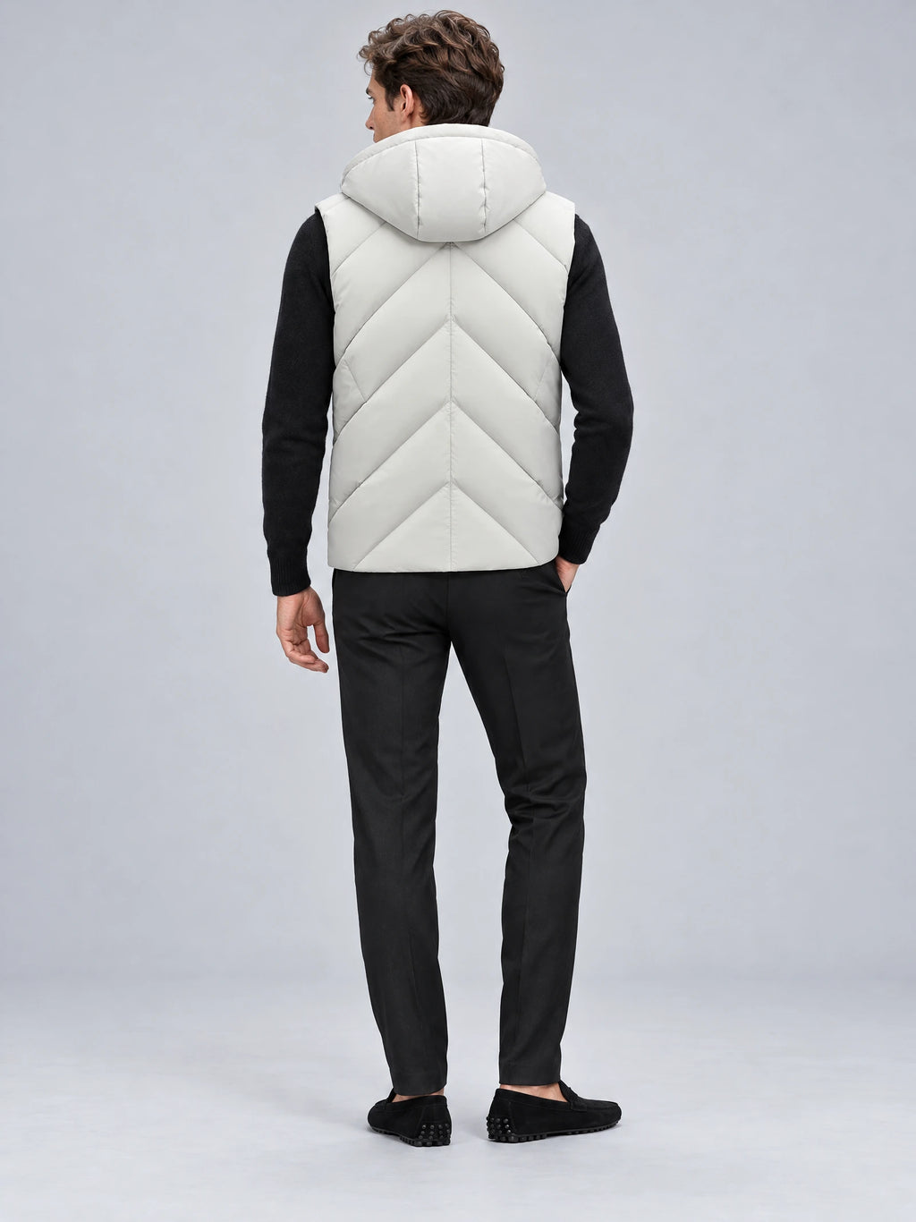 Rear studio view of a model wearing a White down vest with a hood and chevron quilting.