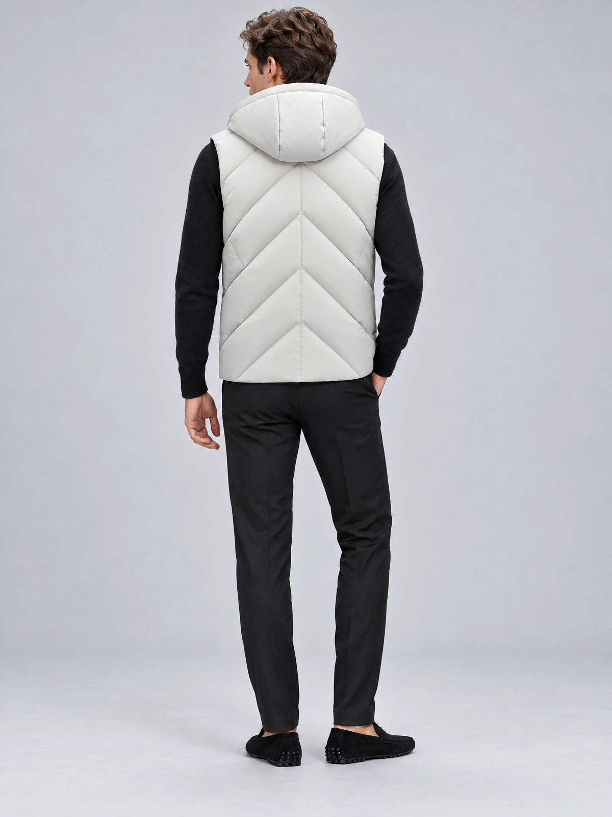 Rear studio view of a model wearing a White down vest with a hood and chevron quilting.