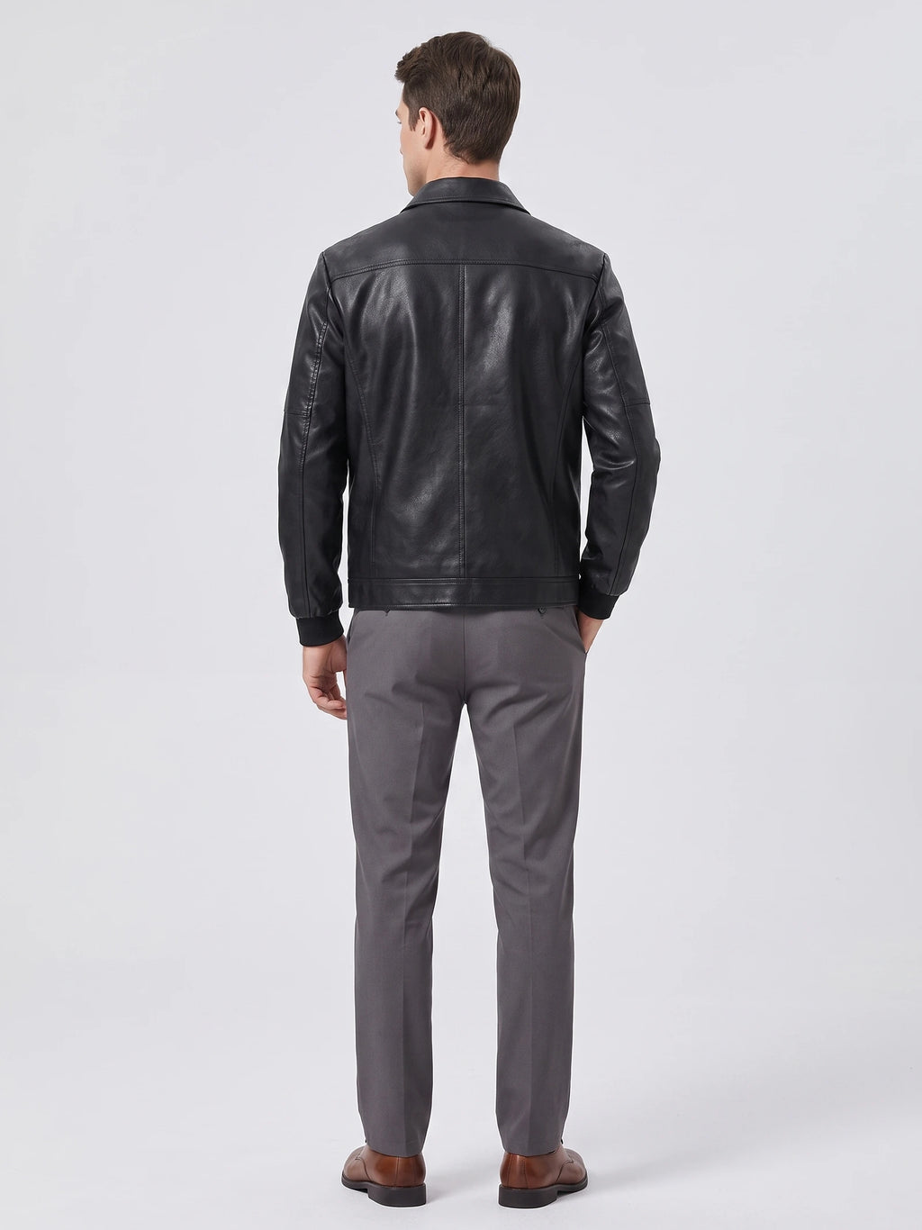 Rear studio view of a model wearing a Black PU leather Fall Jacket with back panel stitching and ribbed cuffs.