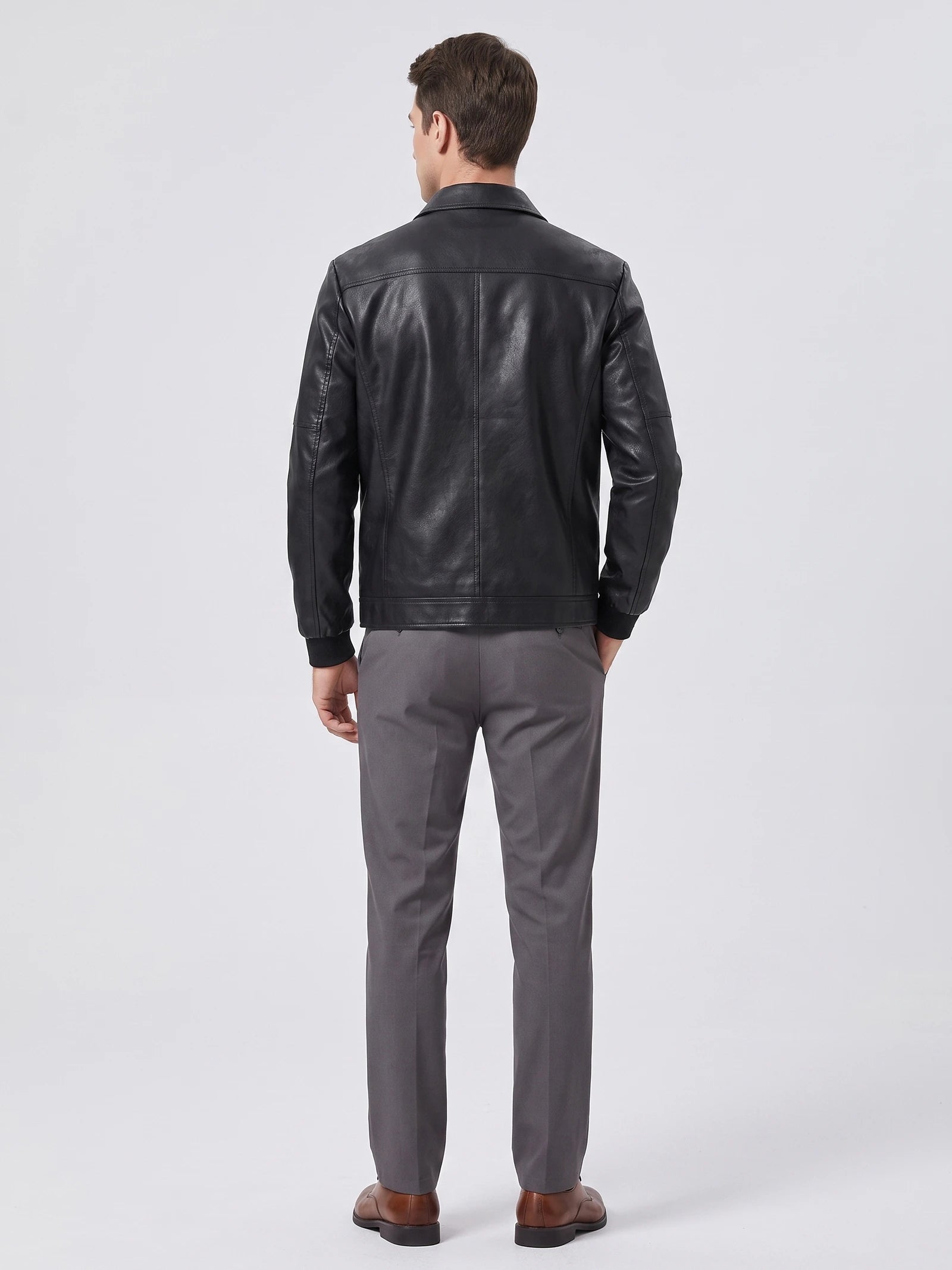 Rear studio view of a model wearing a Black PU leather Fall Jacket with back panel stitching and ribbed cuffs.