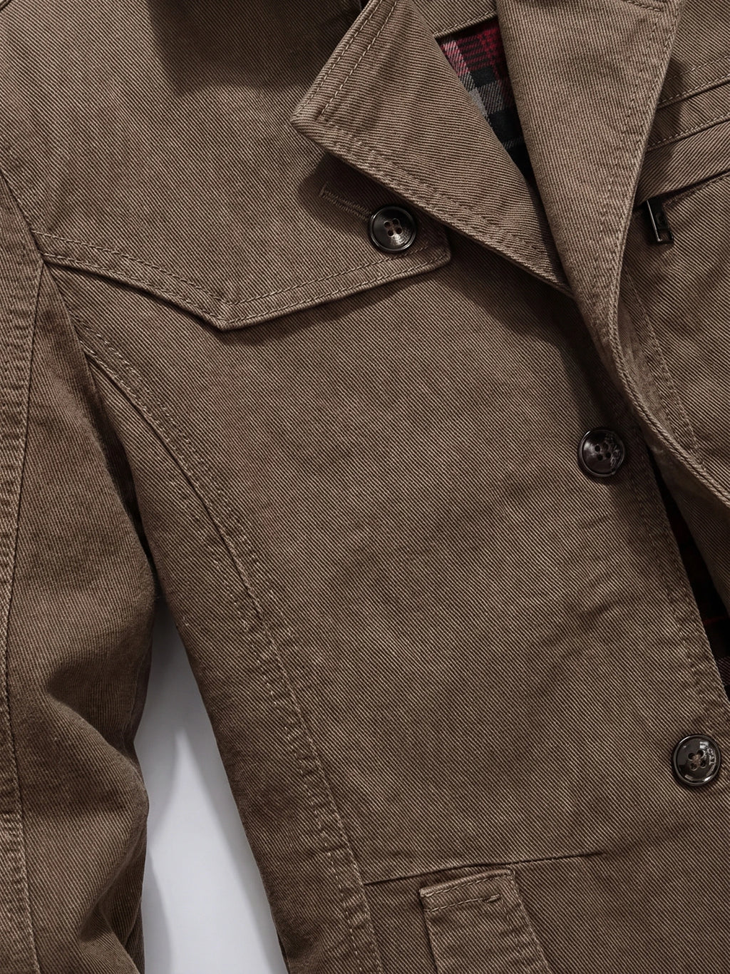 Close-up of the Brown cotton Fall Trench Coat showing its peaked lapel, double-breasted buttons, belted waist, and stitched pocket flap.