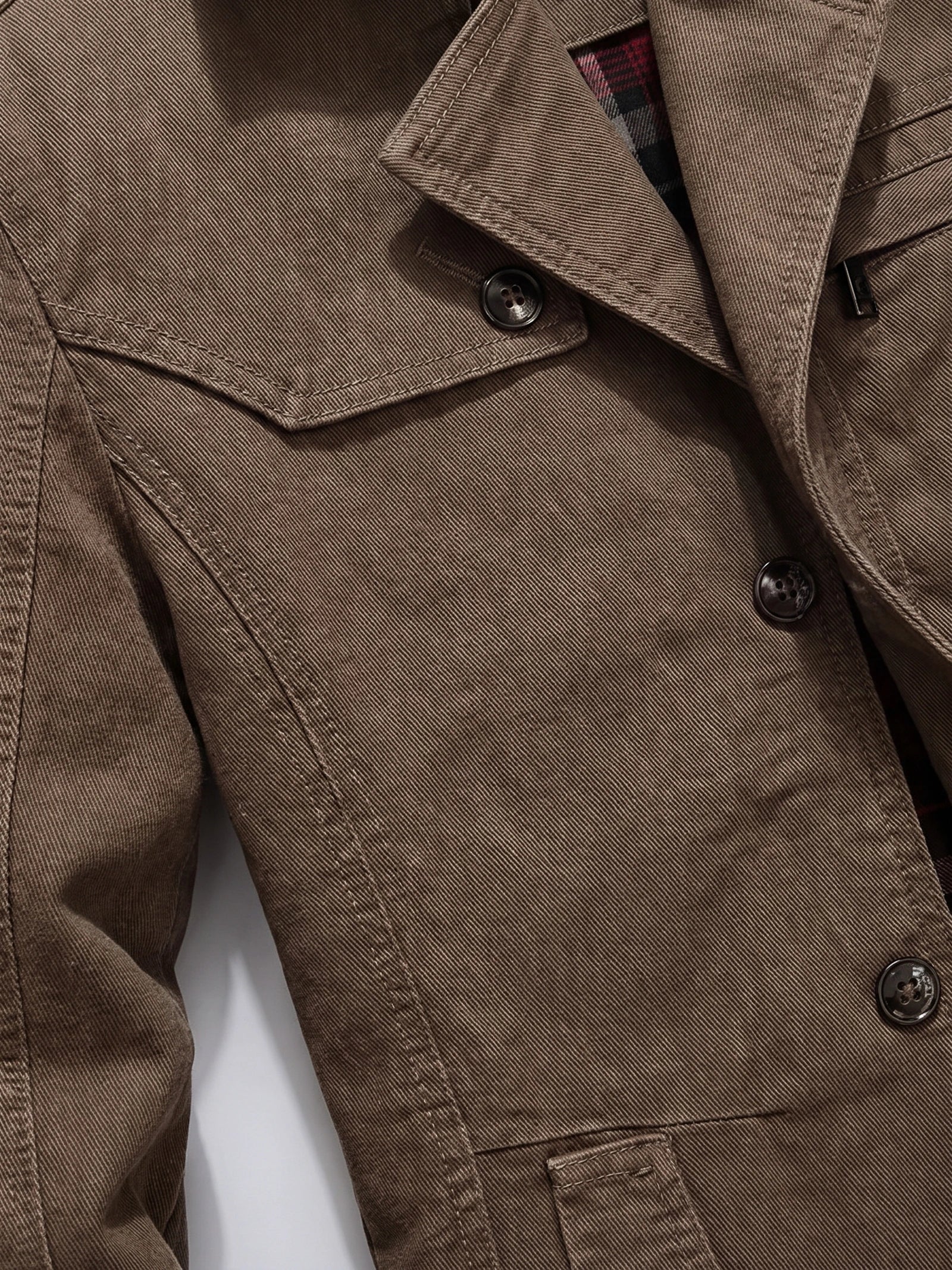 Close-up of the Brown cotton Fall Trench Coat showing its peaked lapel, double-breasted buttons, belted waist, and stitched pocket flap.