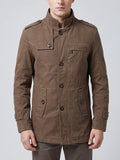 Front studio view of a model wearing a Brown cotton Fall Trench Coat with a stand collar, button closure, shoulder tabs, and multiple pockets.