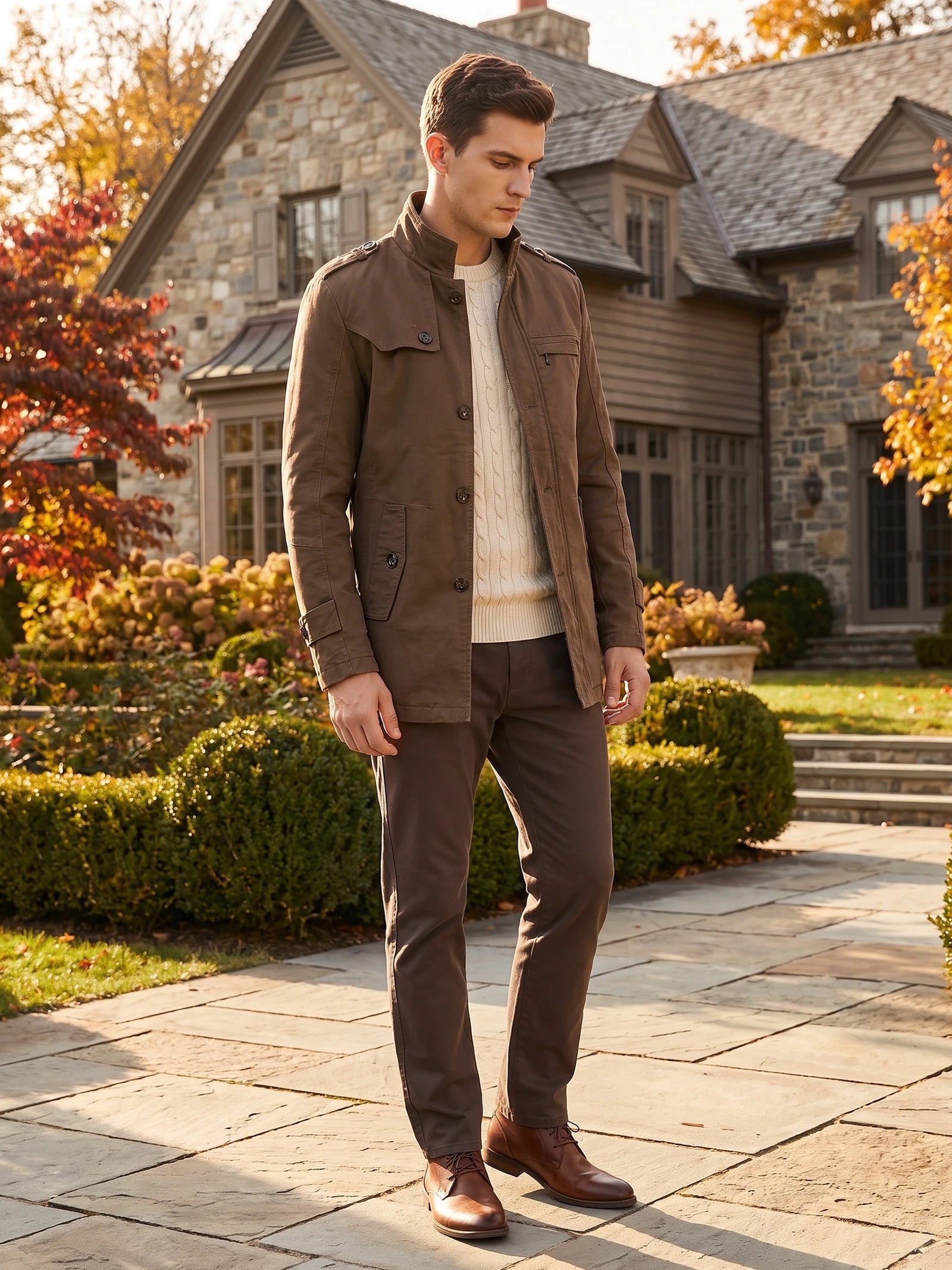 Man wearing a Brown cotton Fall Trench Coat with buttoned pockets on a garden path outside a home.