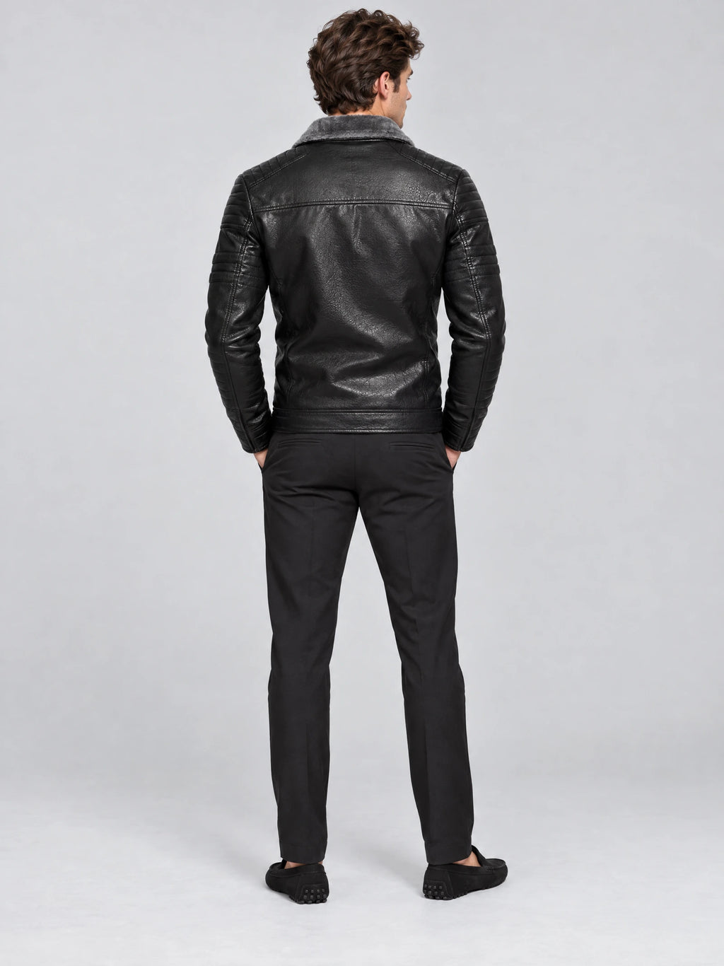 Rear studio view of a model wearing a Black leather aviator jacket with a shearling-style collar and quilted sleeves.