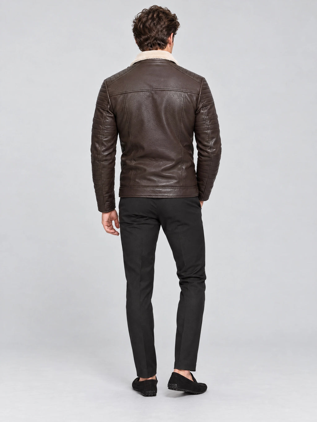 Rear studio view of a model wearing a Brown leather aviator jacket with a shearling-style collar and quilted sleeves.
