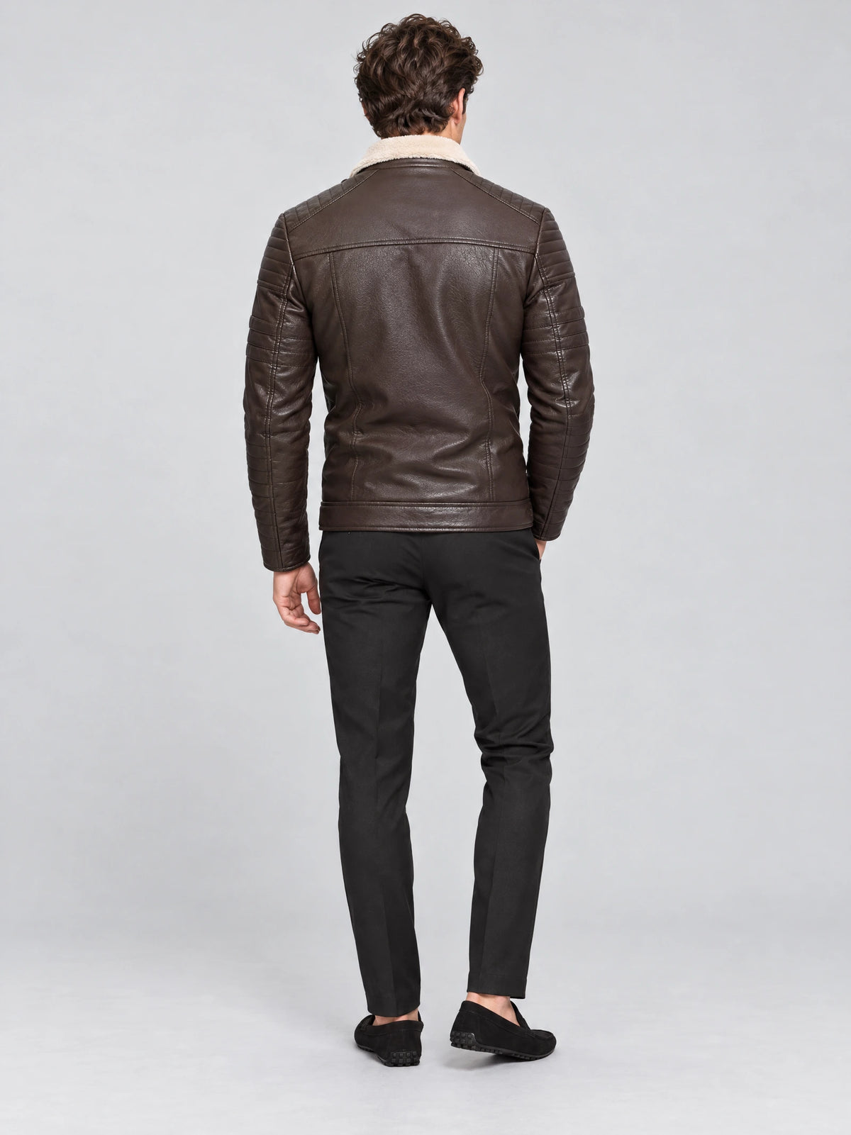 Rear studio view of a model wearing a Brown leather aviator jacket with a shearling-style collar and quilted sleeves.