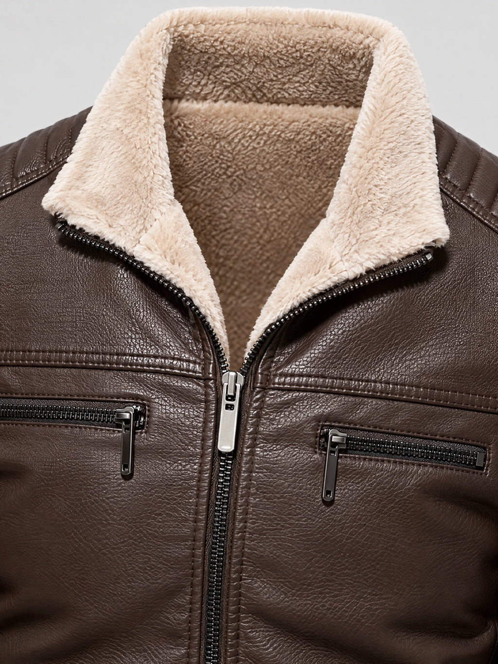 Close-up of a Brown leather aviator jacket with a plush fleece collar, front zipper, and zippered chest pockets.