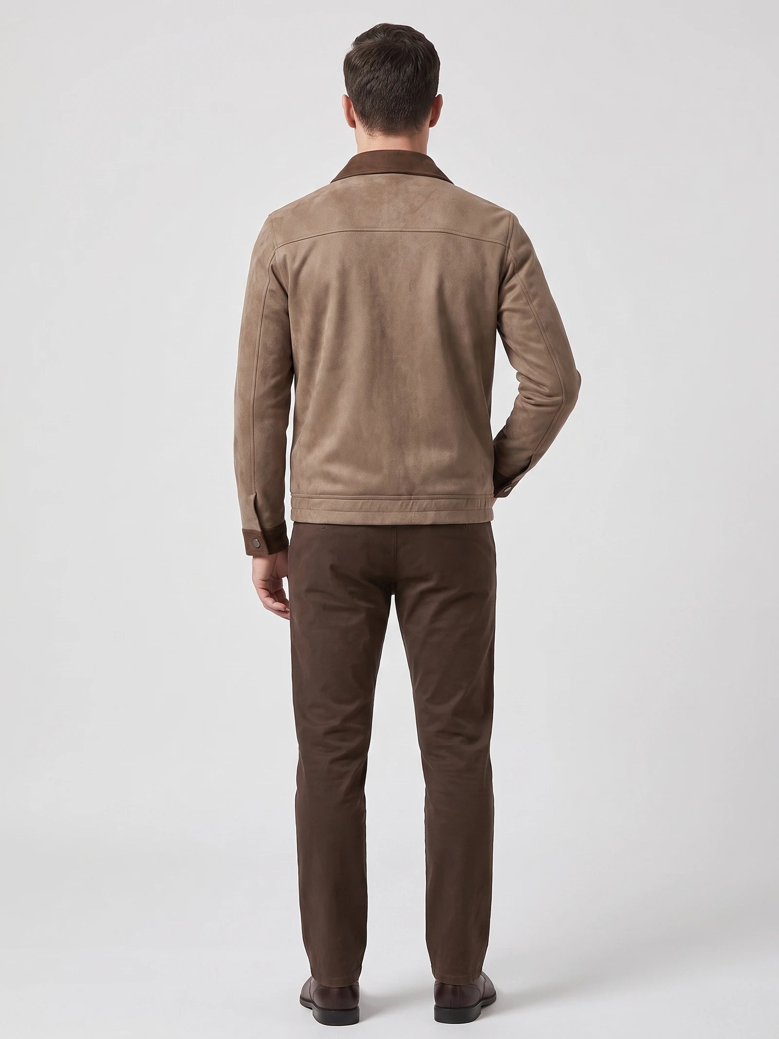 Rear studio view of a model wearing a Brown faux Suede Jacket with a back yoke seam and buttoned cuffs.