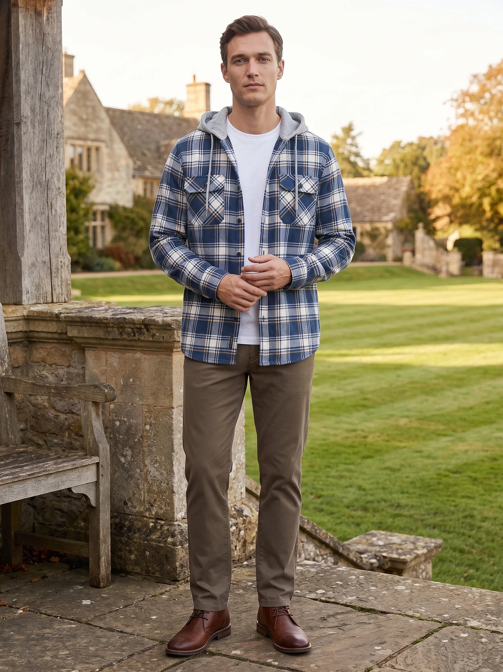 Model wearing a Blue plaid Flannel Jacket with a hood and chest pockets beside a stone terrace and garden.