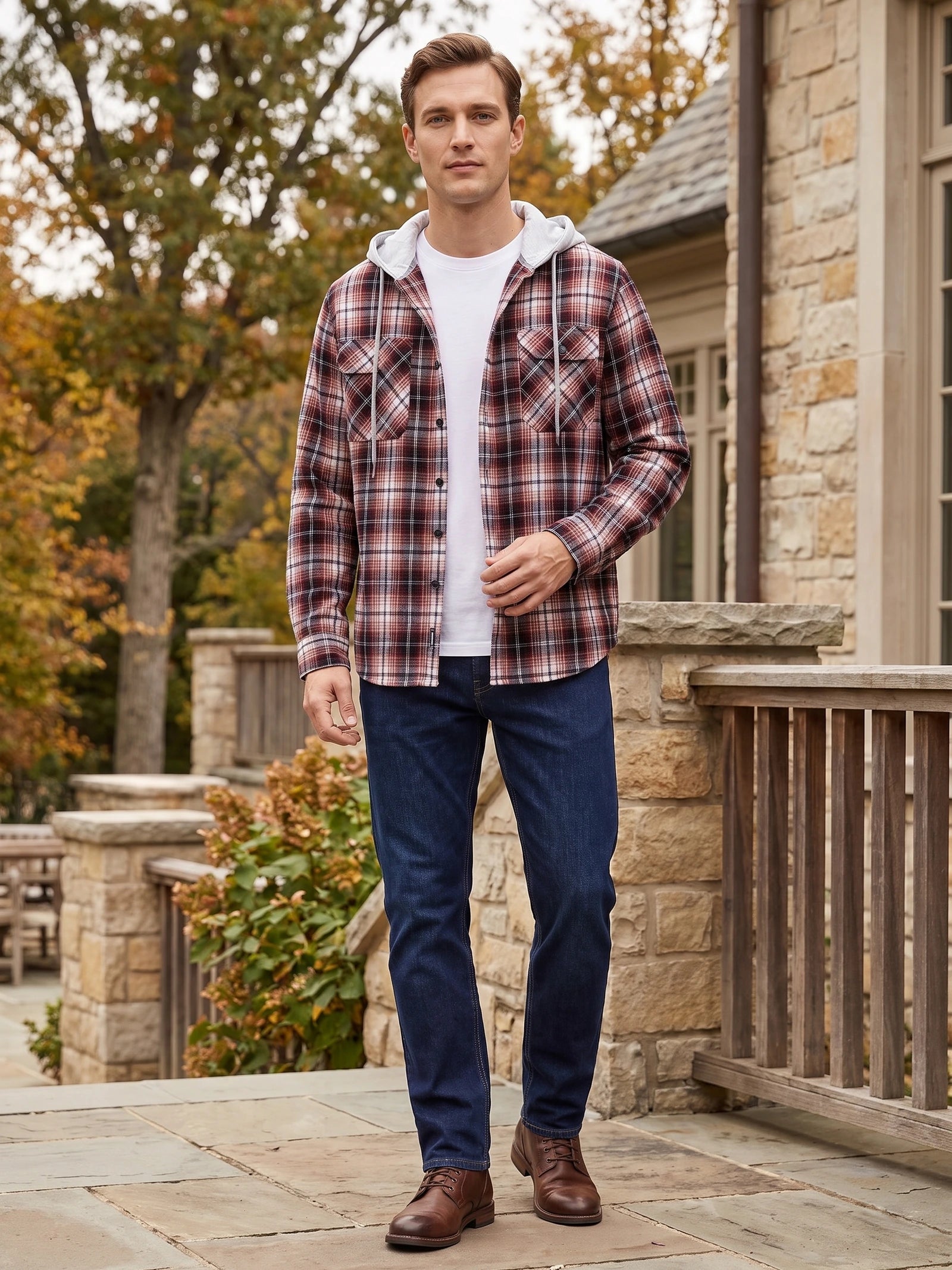 Model wearing a Red plaid hooded Flannel Jacket with chest pockets while walking beside a stone house.