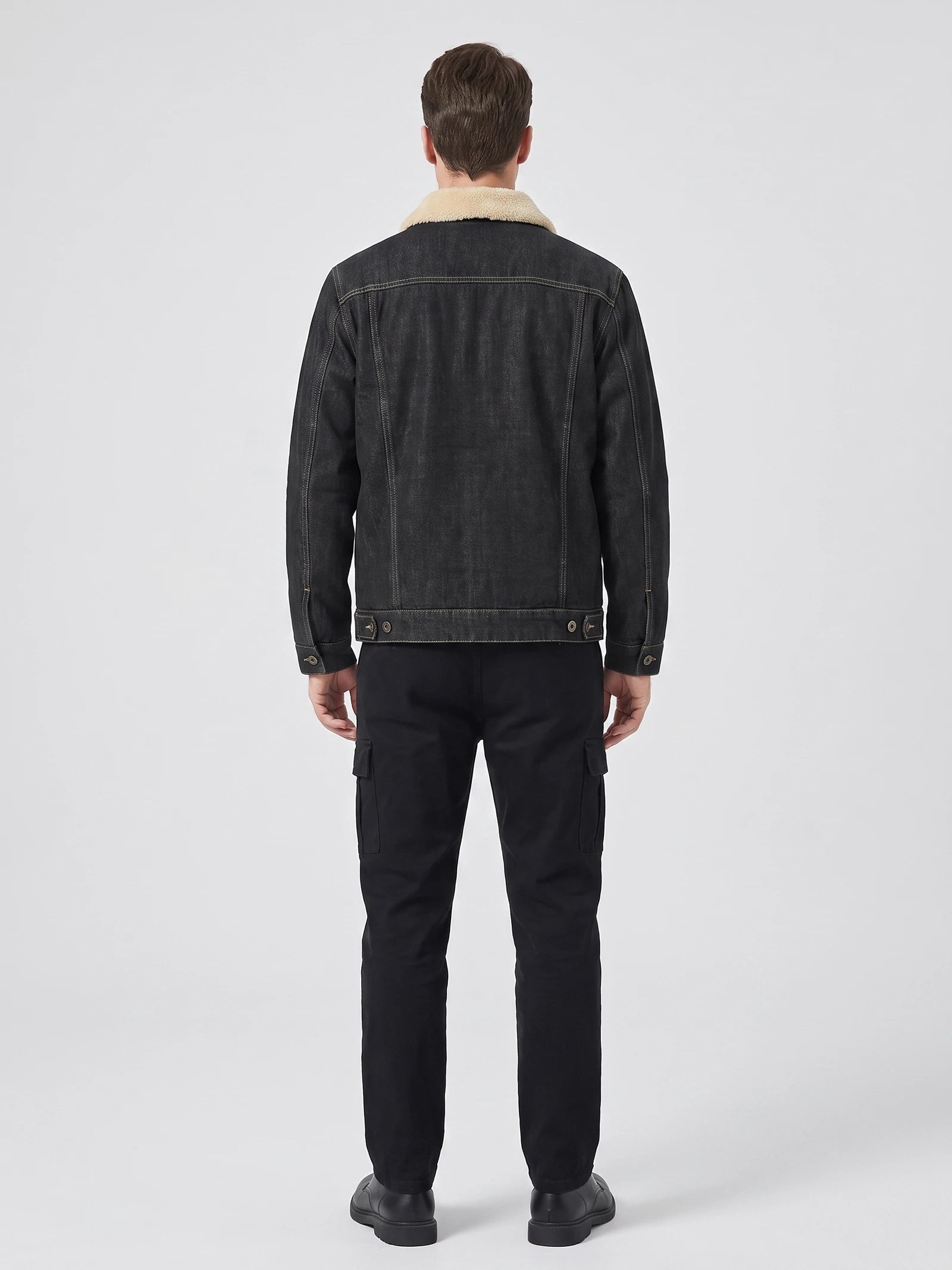 Rear studio view of a model wearing a Black fleece jacket with a shearling-style collar, stitched back panels, and button-adjustable hem.