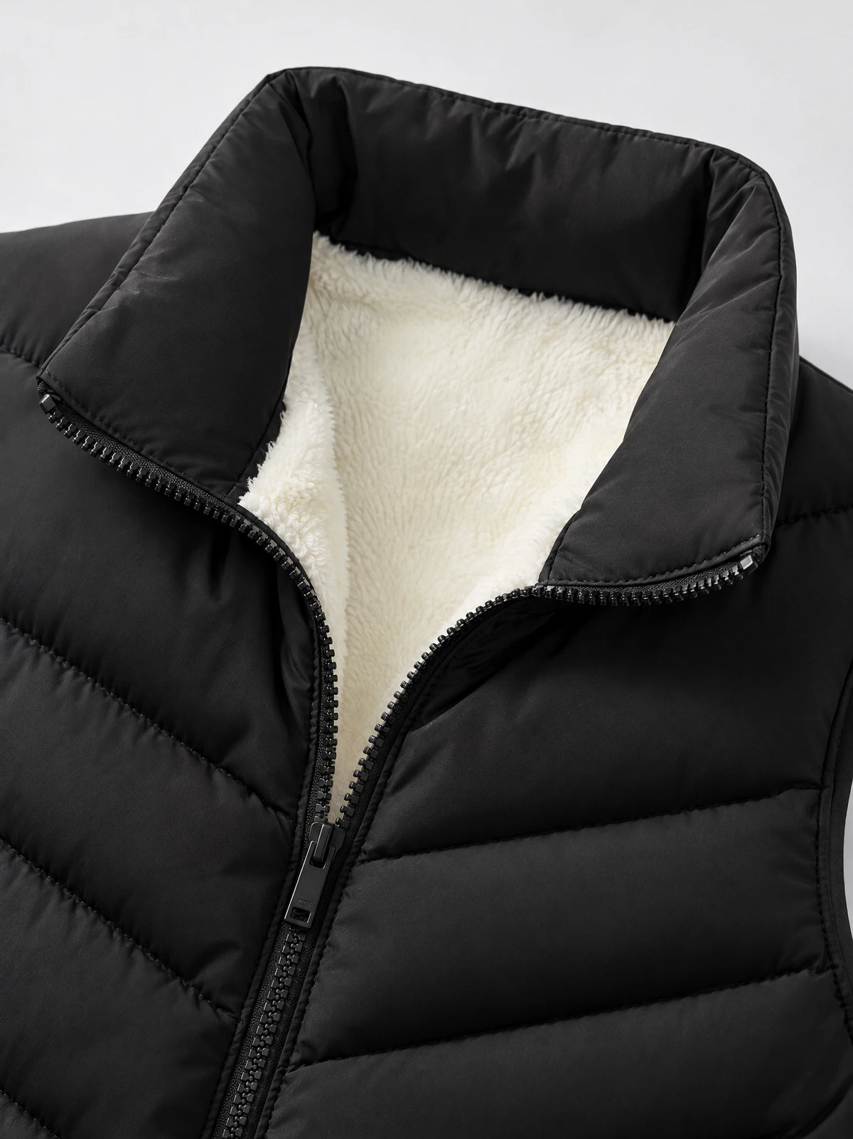 Close-up of a Black fleece-lined puffer vest with a stand collar, quilted stitching, and front zipper.