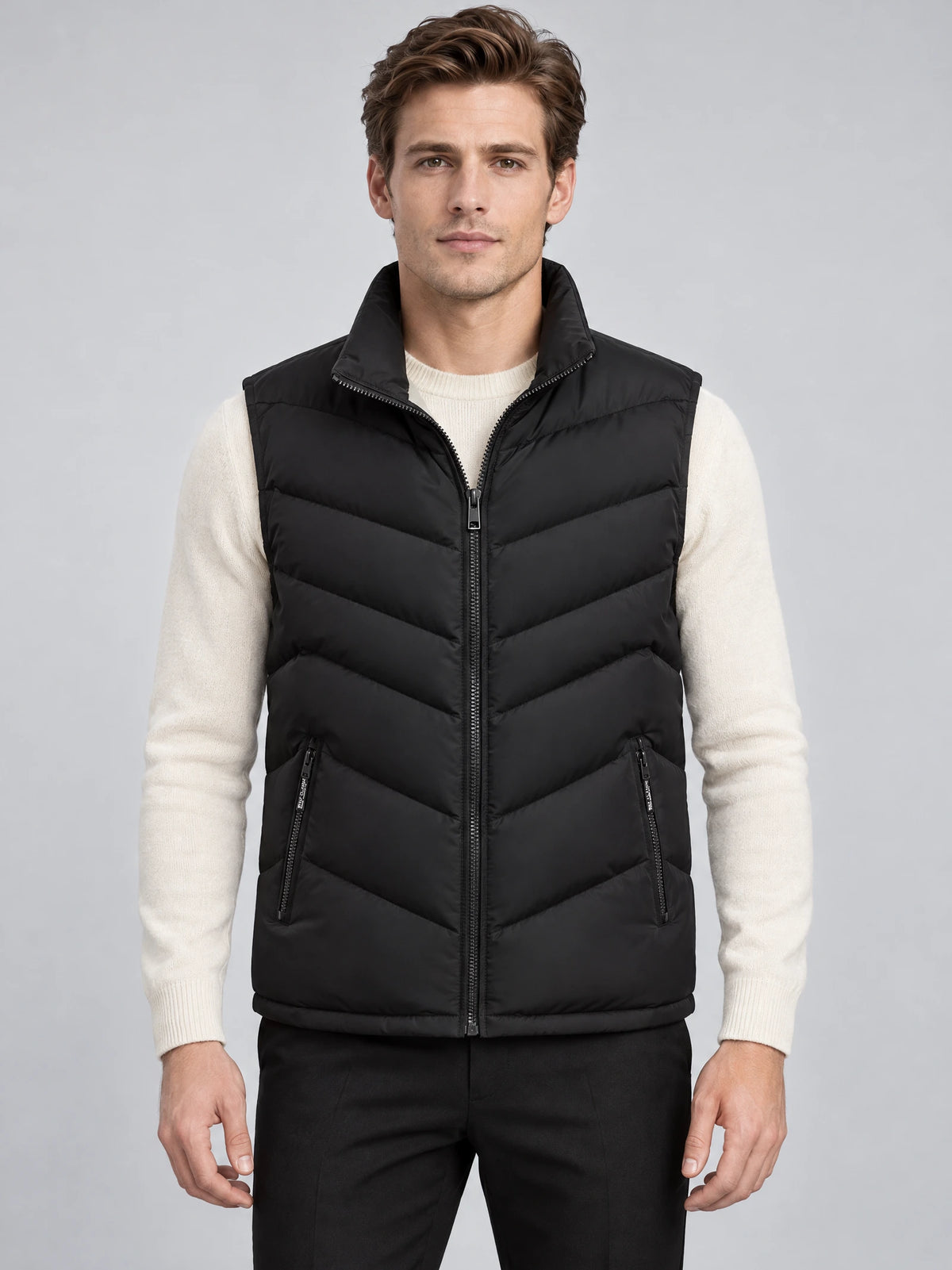 Front studio view of a model wearing a Black fleece lined puffer vest with a stand collar, zip front, chevron quilting, and zip pockets.