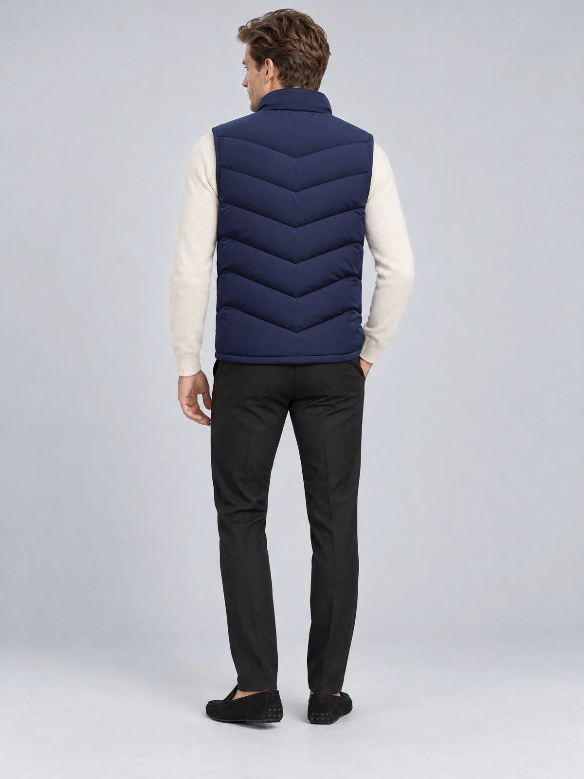 Rear studio view of a model wearing a Navy Fleece Lined Puffer Vest with a stand collar and chevron quilting.