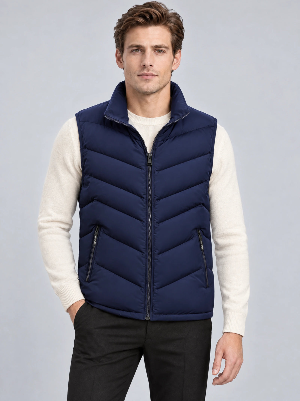 Front studio view of a model wearing a Navy fleece lined puffer vest with a stand collar, zip front, chevron quilting, and zip pockets.