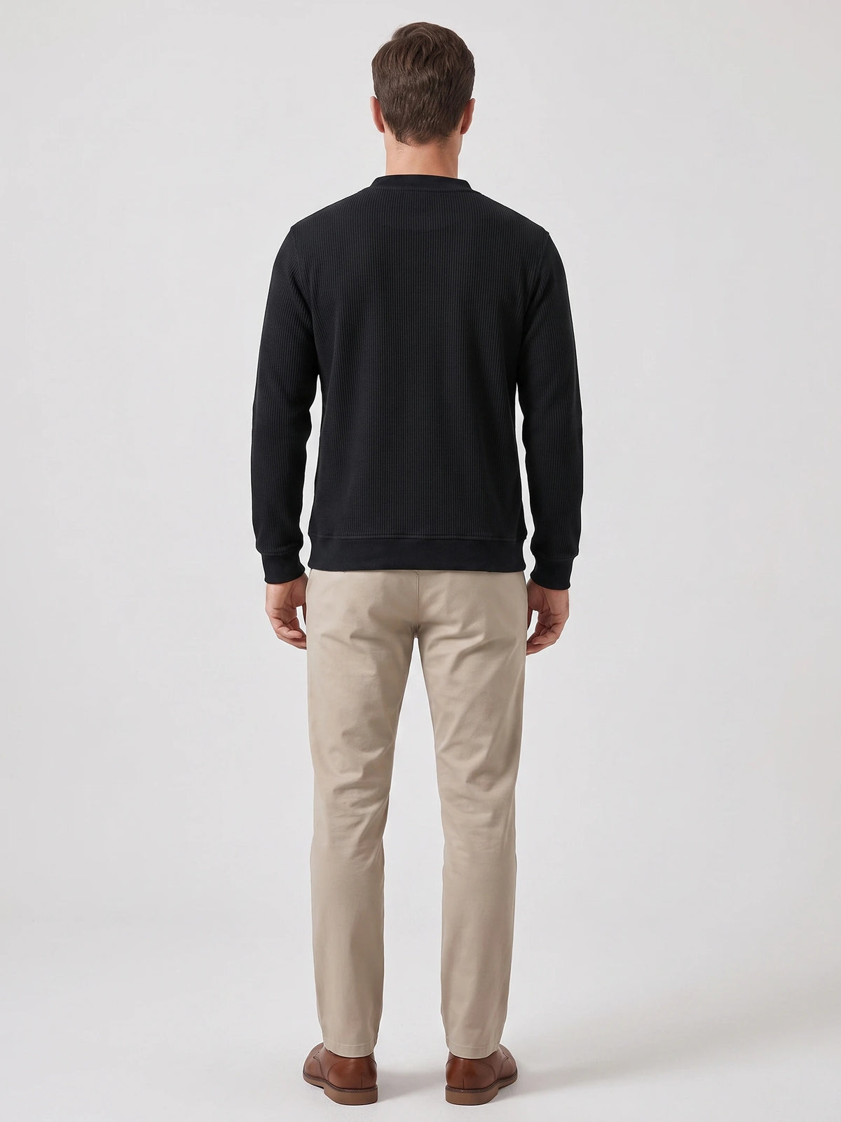 Rear studio view of a model wearing a Black fleece lined sweater with long sleeves and ribbed cuffs and hem.