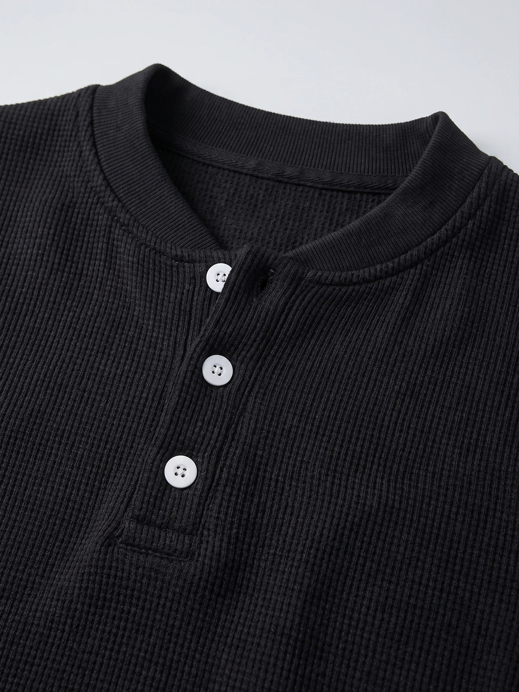 Close-up of the Black men's Fleece Lined Sweater with a ribbed knit texture, crew neckline, and three-button Henley placket.