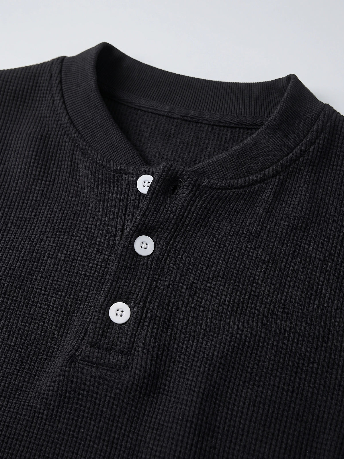 Close-up of the Black men's Fleece Lined Sweater with a ribbed knit texture, crew neckline, and three-button Henley placket.