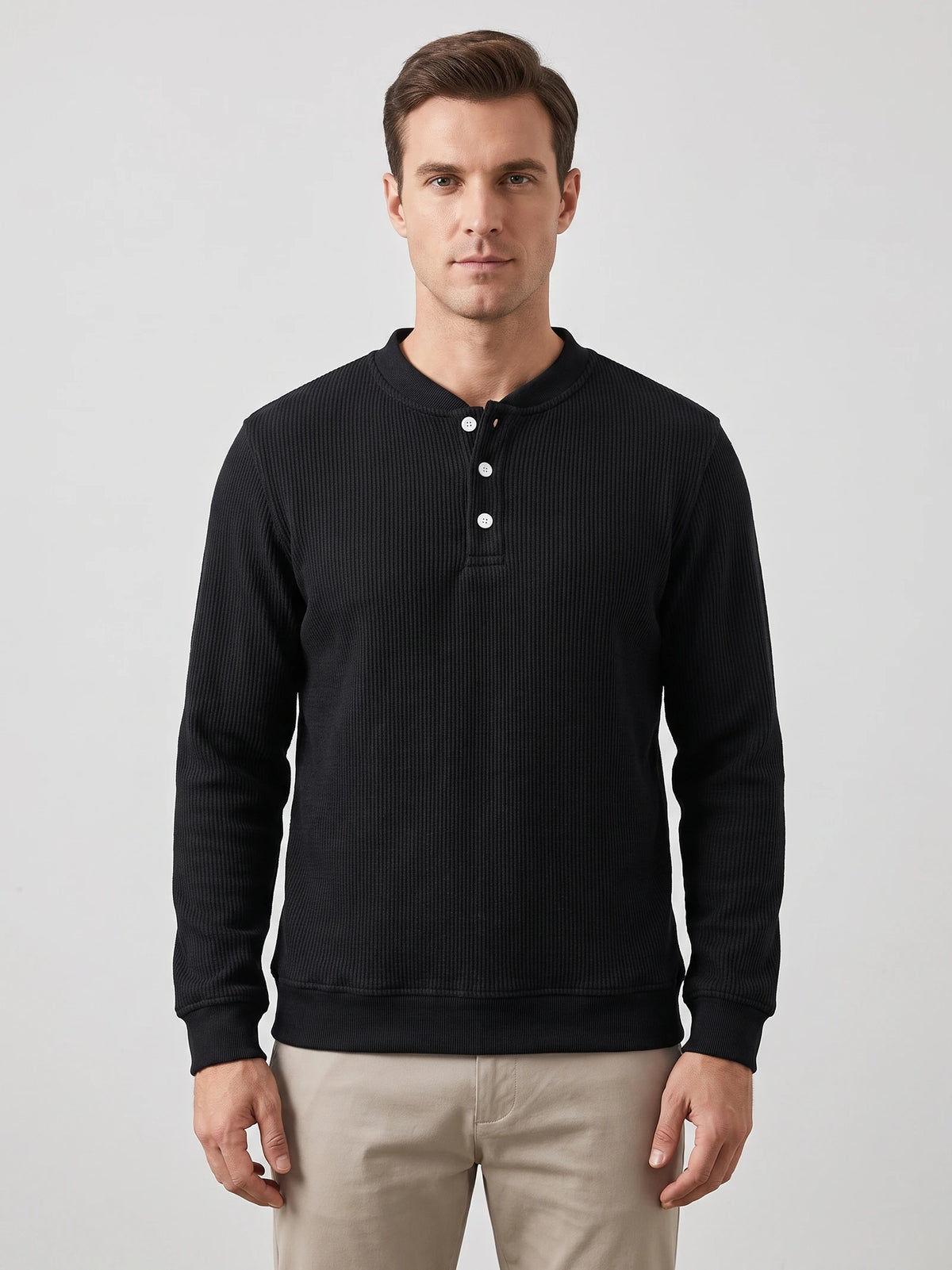 Front studio view of a model wearing a Black fleece lined sweater with ribbed texture, long sleeves, and a three-button Henley placket.