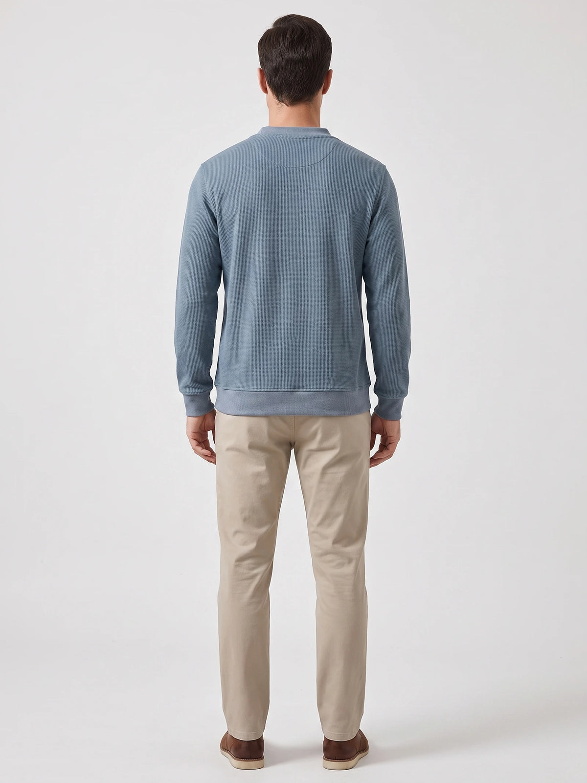 Rear view of a model wearing a Blue fleece lined sweater with long sleeves, ribbed cuffs, and hem.