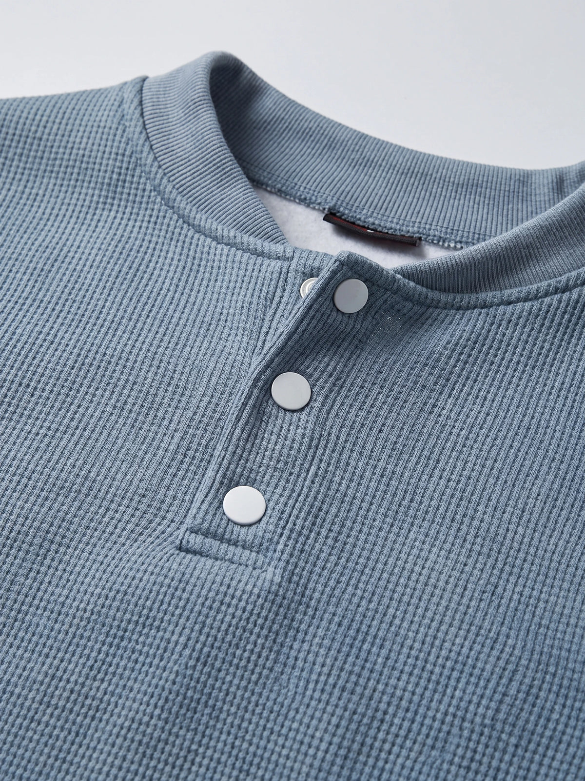 Close-up of the Blue men's Fleece Lined Sweater with a ribbed knit texture, crew neckline, and three-button Henley placket.