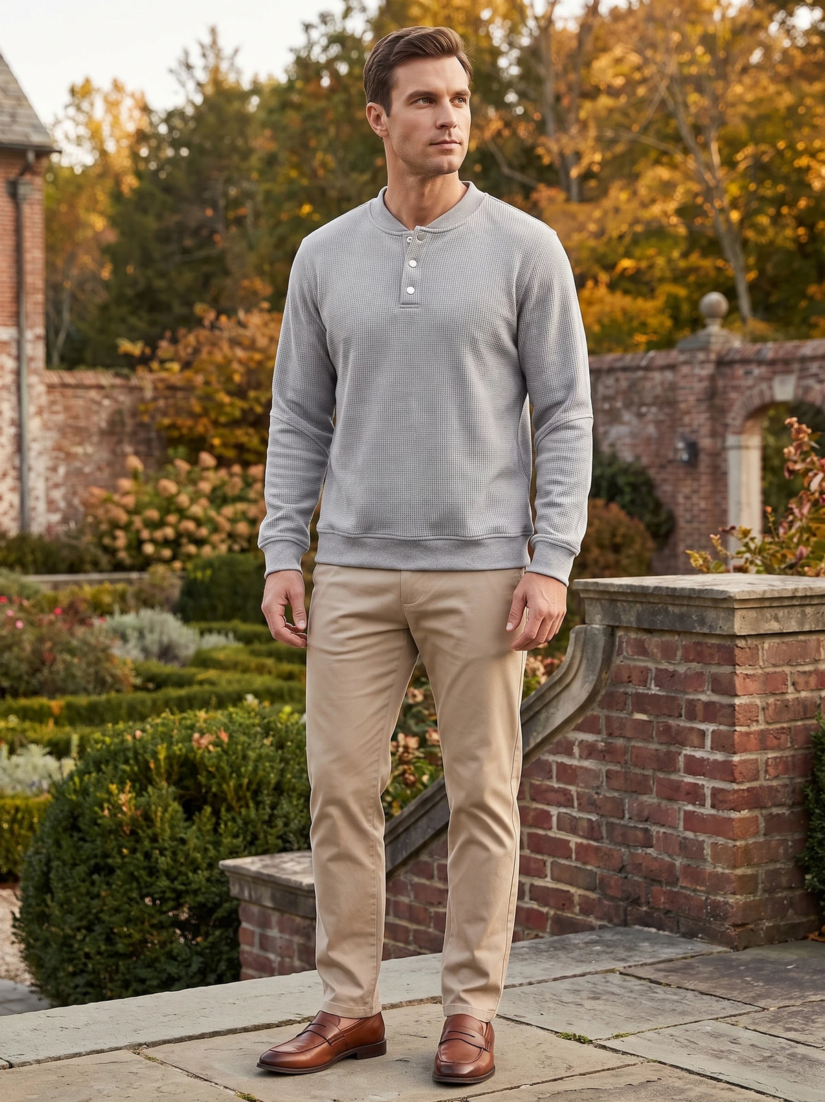 Model wearing a Gray fleece lined Henley sweater with a button placket in a landscaped garden.
