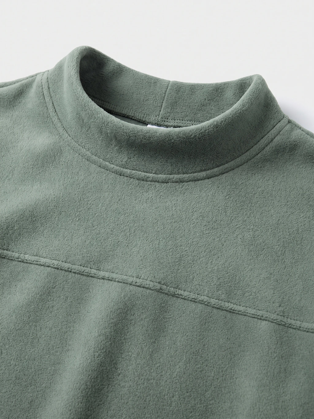 Close-up of the Green men’s fleece sweater showing its mock neck, soft texture, and curved chest seam.
