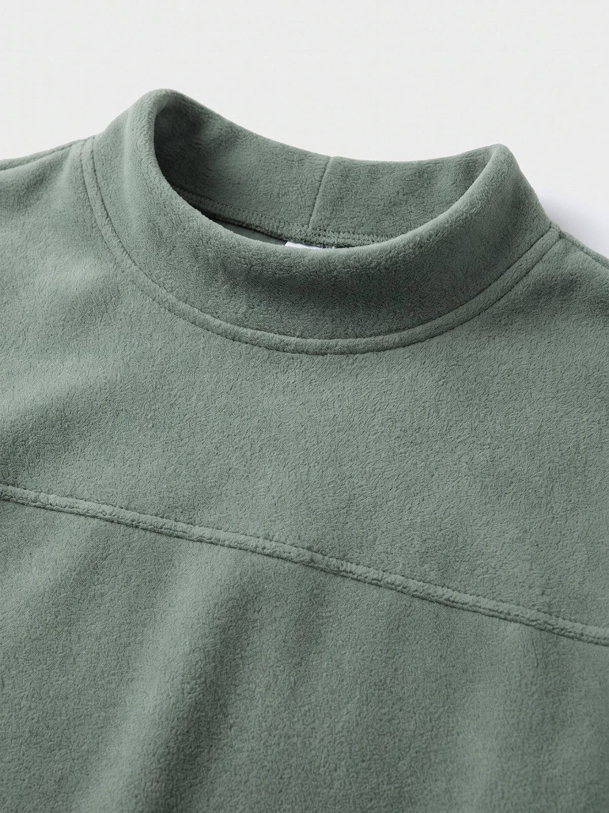 Close-up of the Green men’s fleece sweater showing its mock neck, soft texture, and curved chest seam.