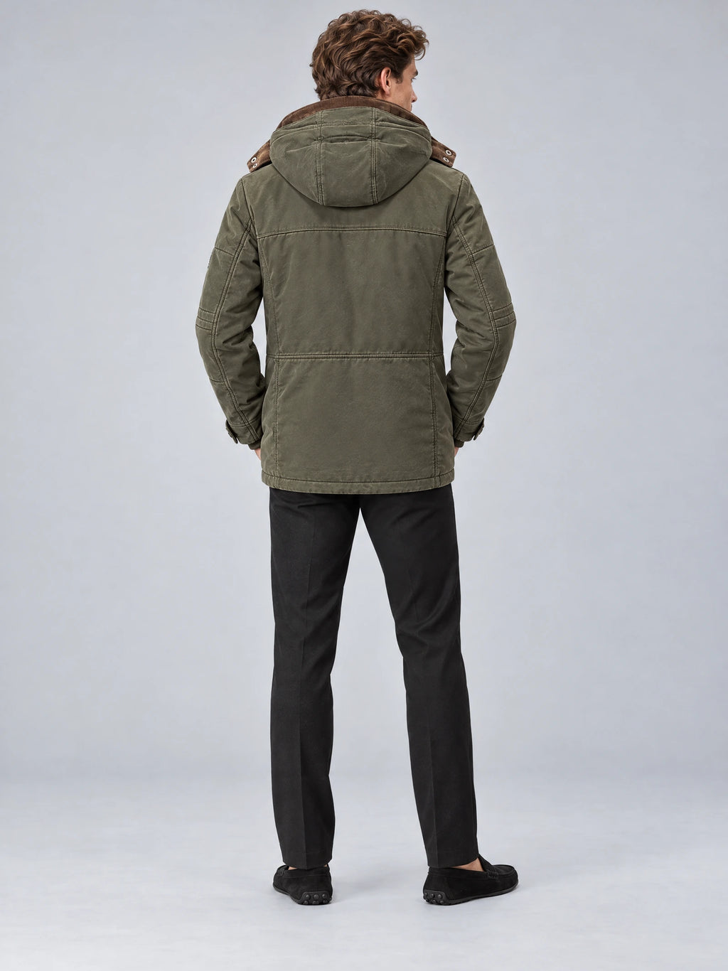 Rear studio view of a model wearing a Green Heavy Winter Jacket with a hood, back seam detailing, and a long parka silhouette.