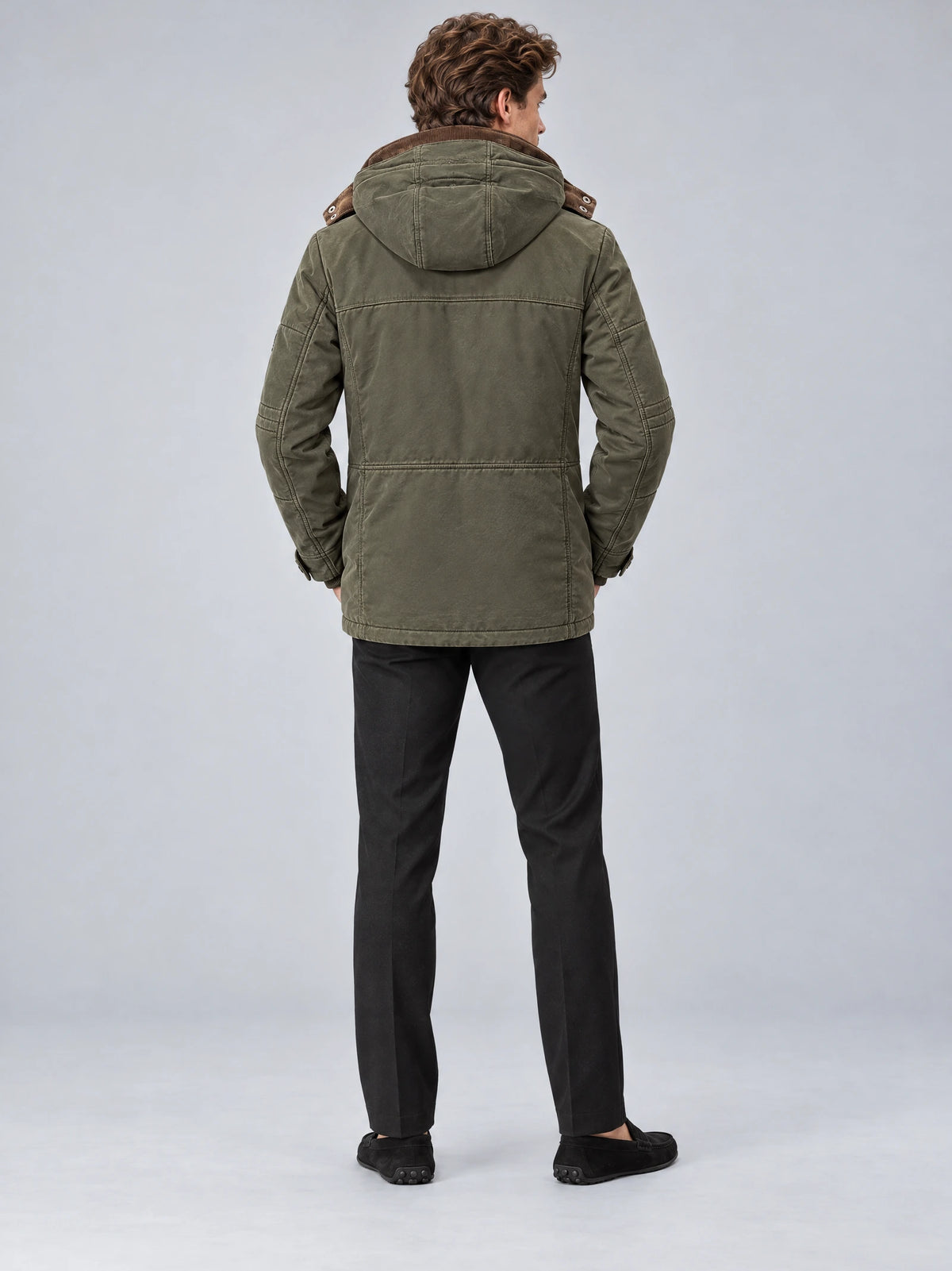 Rear studio view of a model wearing a Green Heavy Winter Jacket with a hood, back seam detailing, and a long parka silhouette.